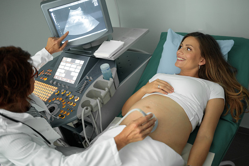 pregnant woman having an ultrasound at doctor's office, female gynecologist
